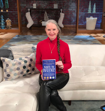 Carla D. Bass, holding her book "Write to Influence!" on set of Great Day Washington. Discussion included her services such as private coaching.