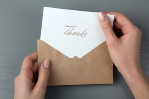 Person holding a thank you note, a critical tool to land a job following a job interview