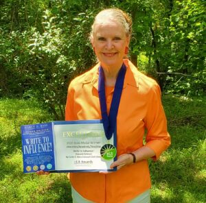 The secret to success is powerful writing. Carla D. Bass, poses with her multiple award-winning book, Write to Influence!